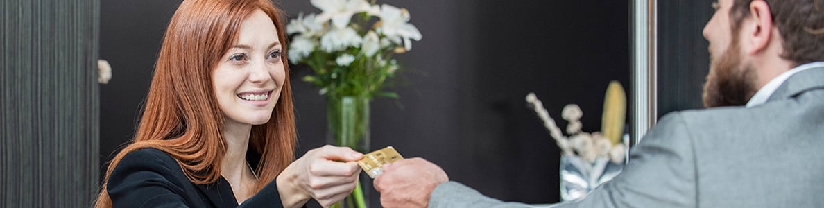 A woman taking a credit card from a man in a suit.