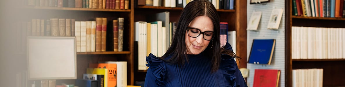 A woman wearing glasses in a library.
