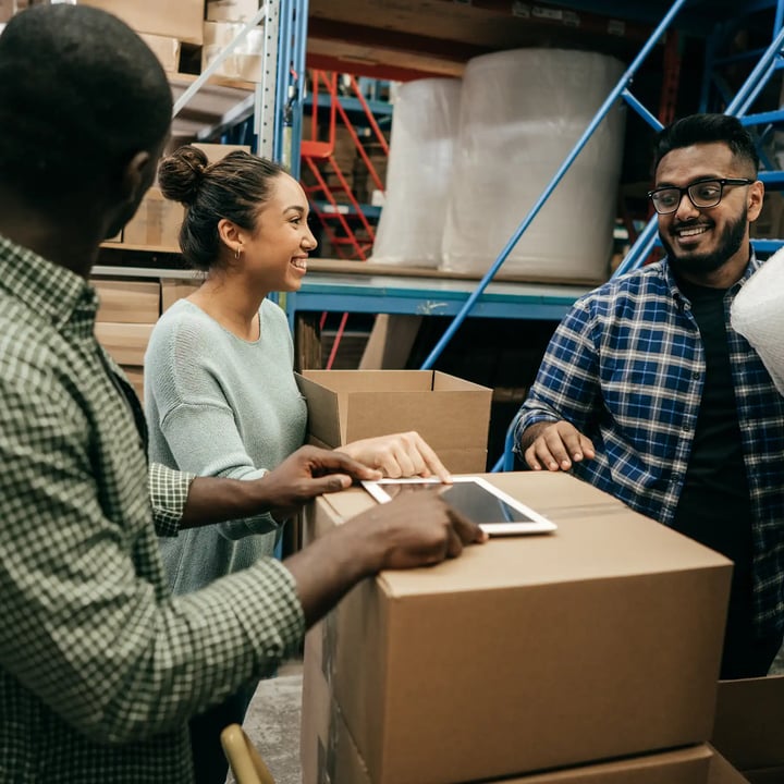 1. Three individuals organizing boxes in a spacious warehouse environment.