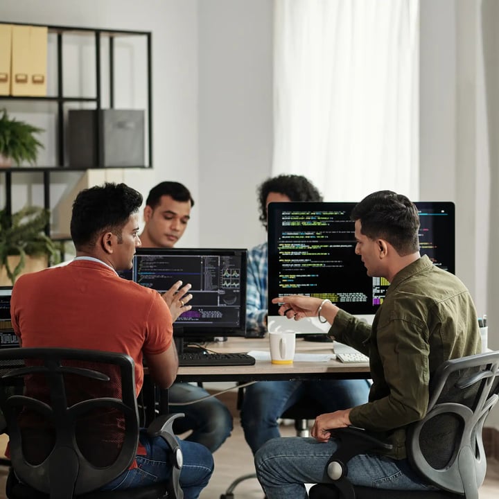 A group of young entrepreneurs sitting aroung table of computers working.