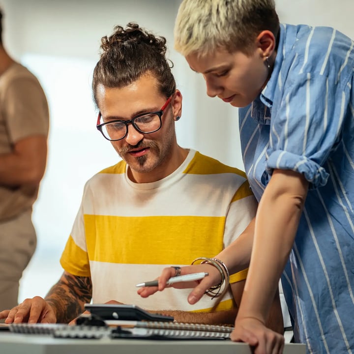 Two co-workers discussing closely looking over a document together.
