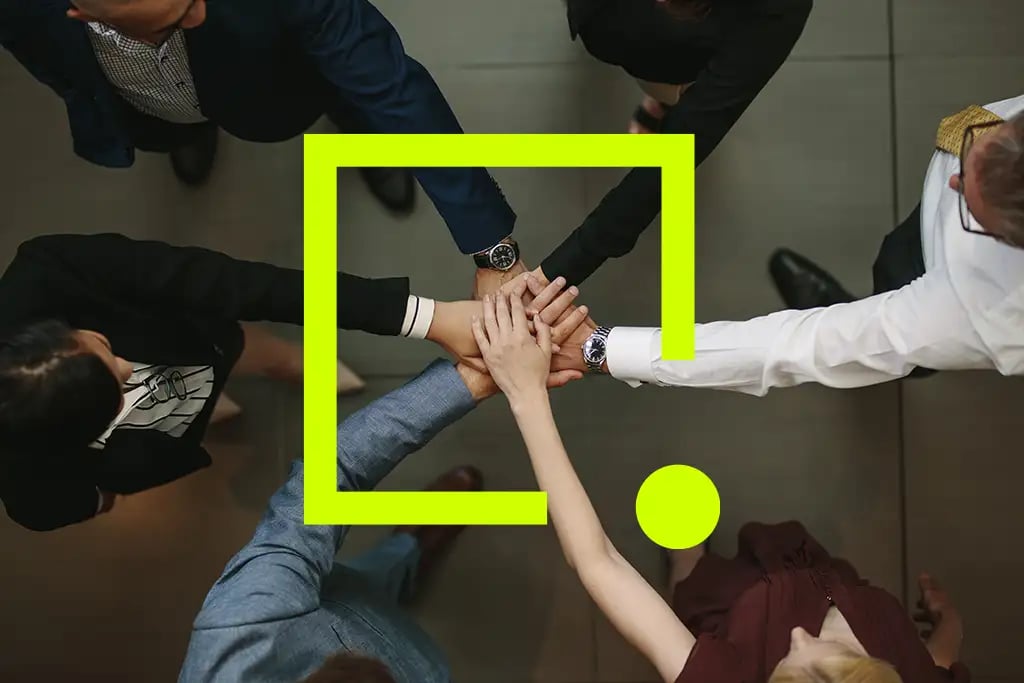 Un groupe de professionnels debout en cercle, se donnant la main dans un geste d'unité et de collaboration.