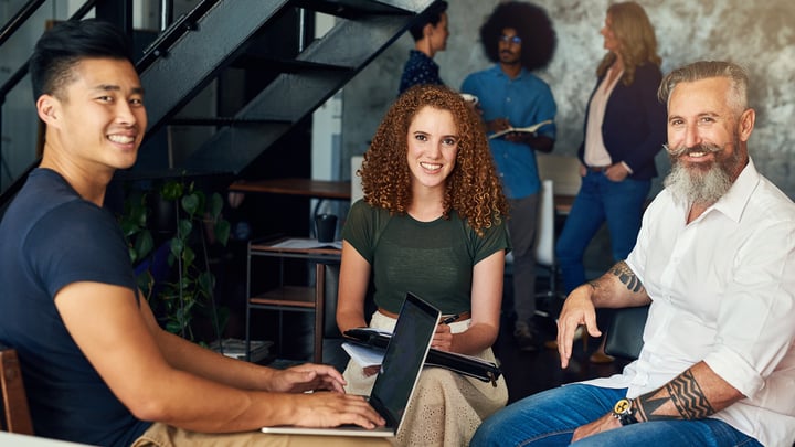 A diverse group of individuals collaborates around a table, each using their laptops for a productive discussion.