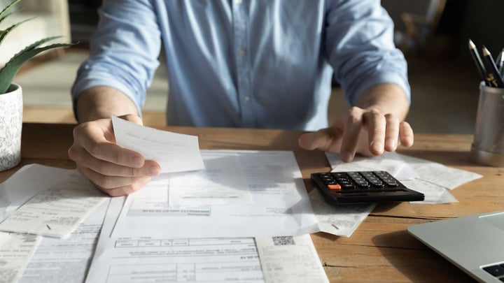 Un homme concentré sur une calculatrice, calculant avec diligence ses obligations fiscales avec une expression sérieuse.