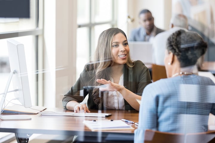 Deux femmes d'affaires discutent autour d'une table dans un bureau professionnel.