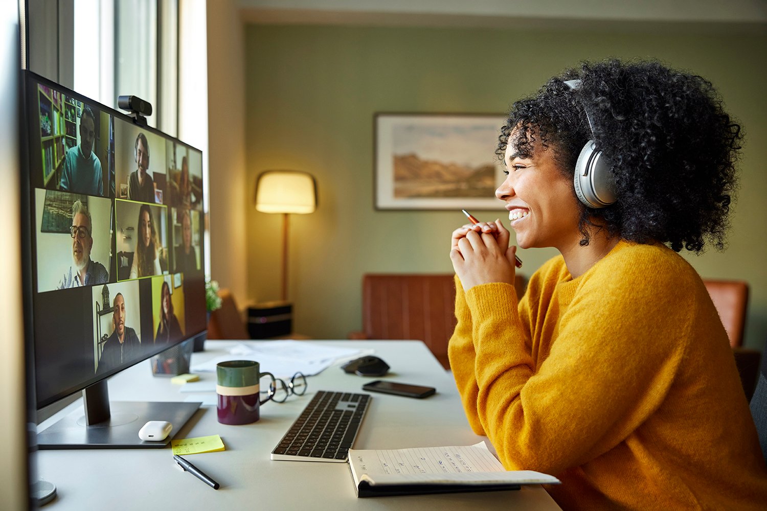 A woman wearing headphones and smiling on a video call.