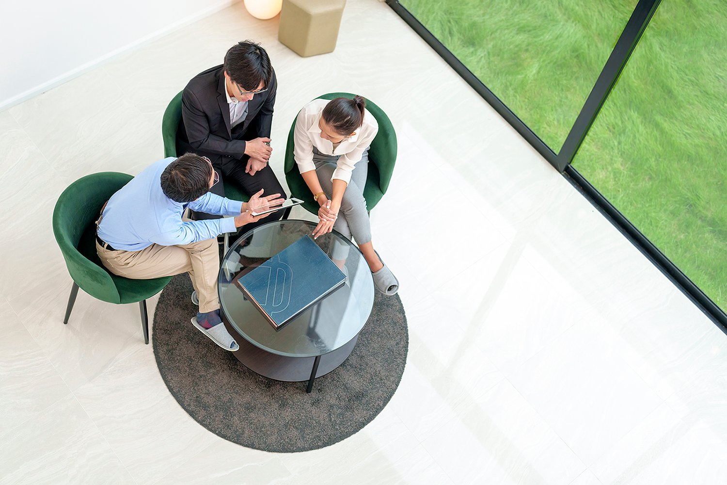 Three business professionals in a meeting around a glass table.