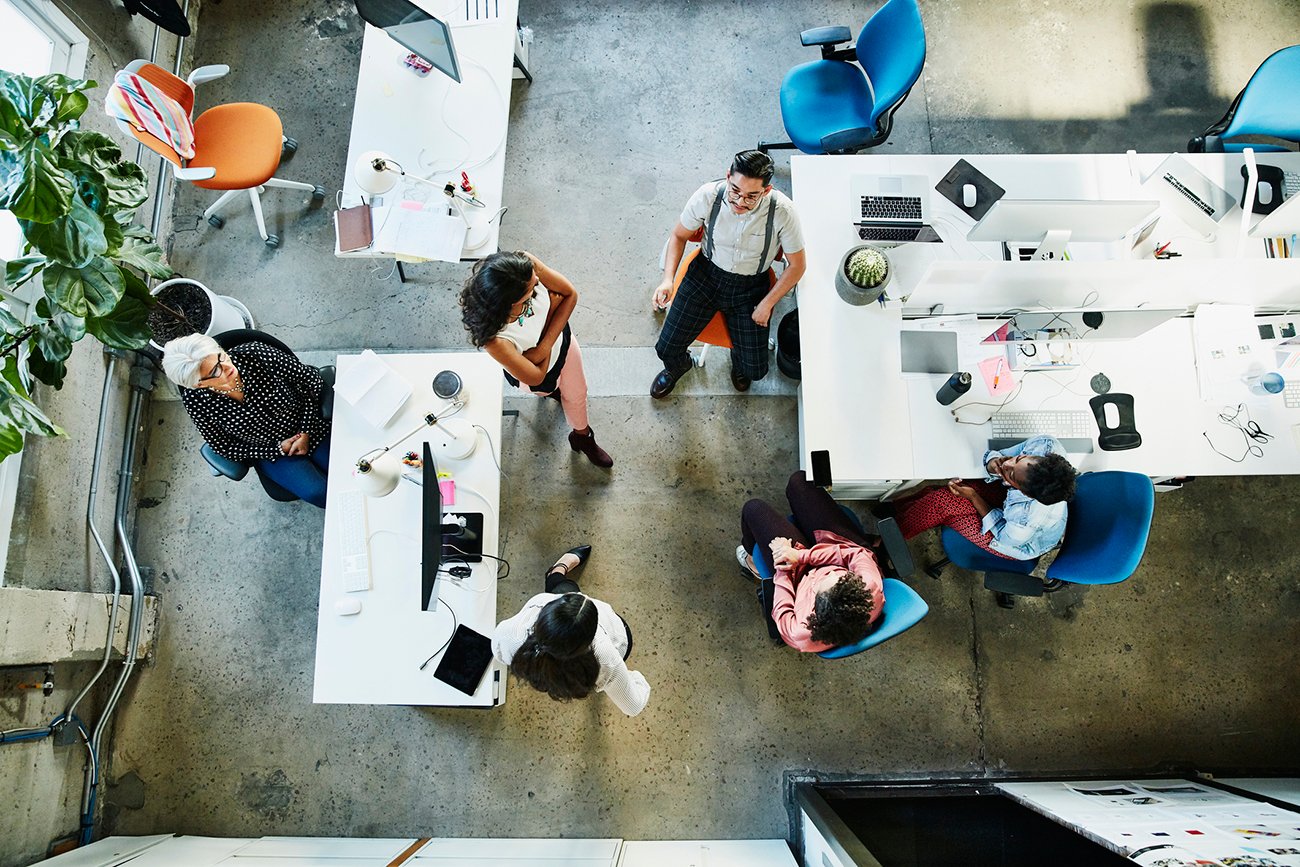 An aerial view of an open concept office with women and men during a business meeting.