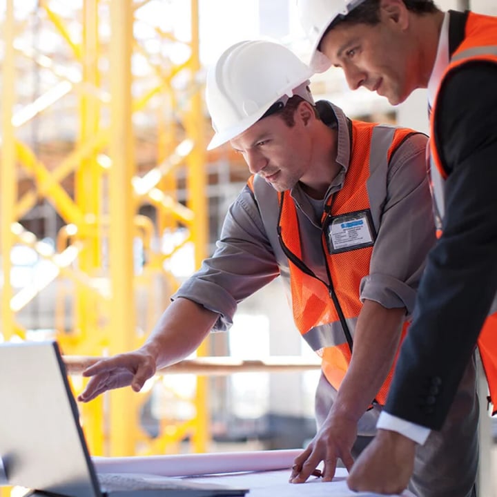 A man wearing ear protection and headphones is focused on his work at a wooden table, ensuring safety and concentration.