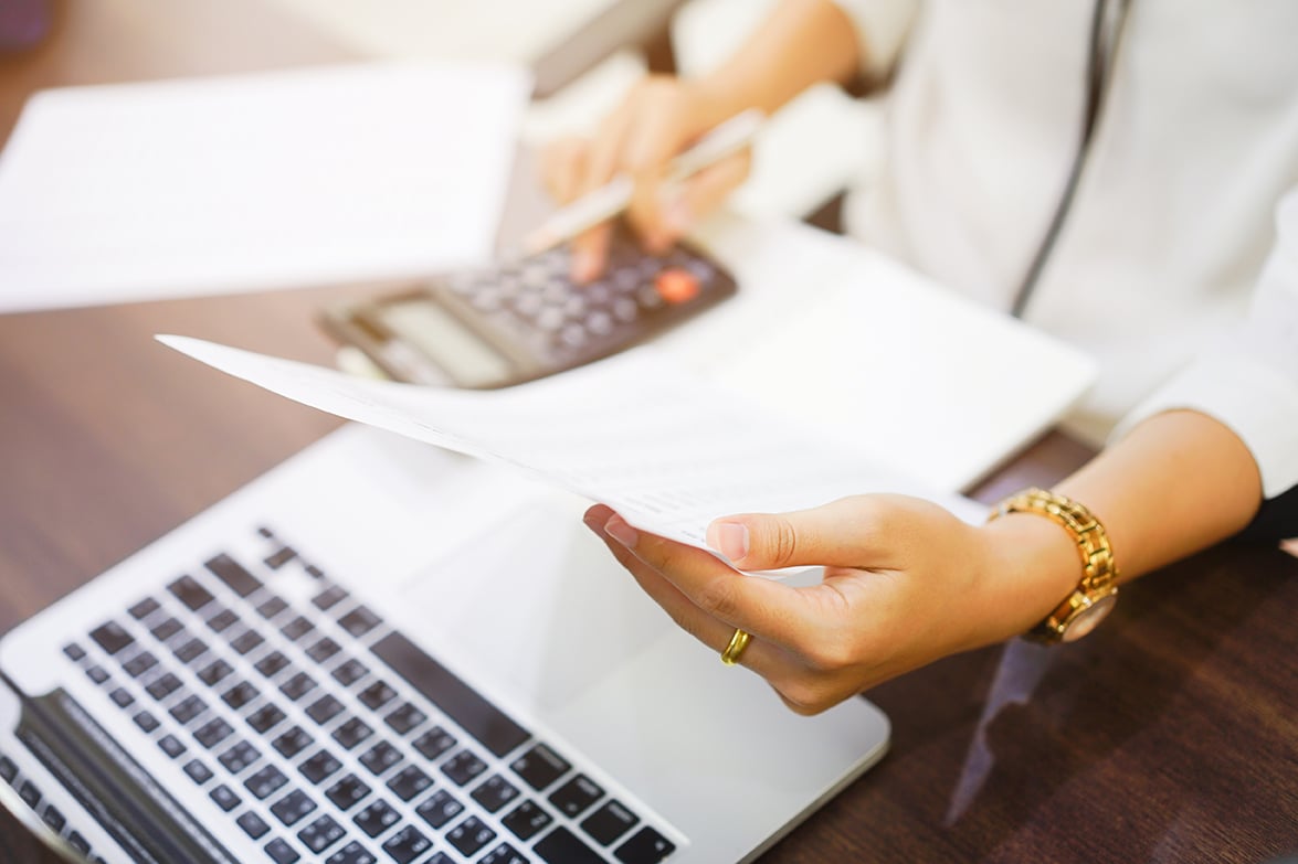 A woman crunching numbers on a calculator and laptop. 