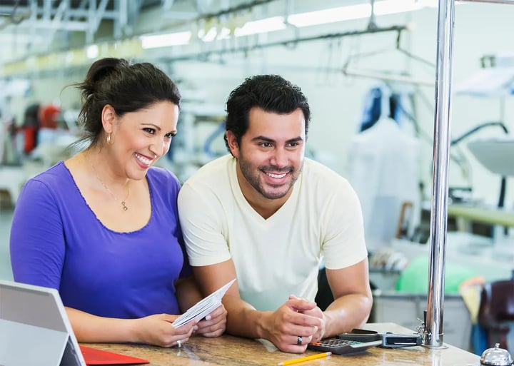 Un homme et une femme sont assis à une table, occupés avec un ordinateur portable devant eux, discutant ou collaborant sur un projet.