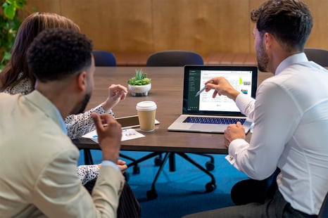 Three white collar employees discussing the Cubeler Business Hub™ on a laptop screen.
