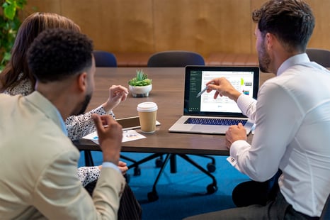 Trois employés discutent du Portail d’affaires Cubeler sur l'écran d'un ordinateur portable.