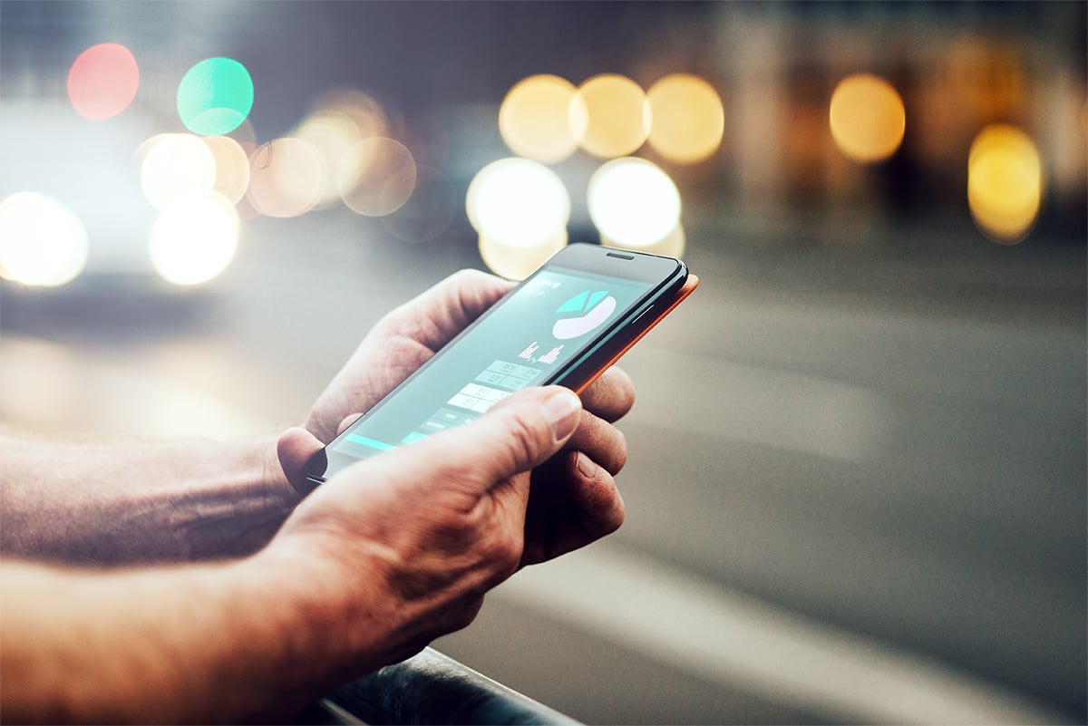 Une main tenant un téléphone portable avec des lumières en arrière-plan