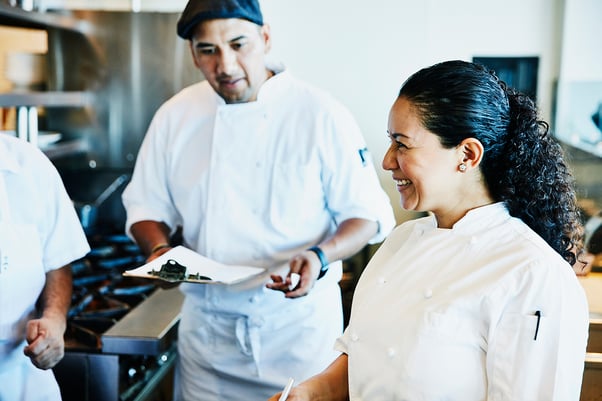 Trois chefs discutent des tâches à accomplir dans la cuisine d'un restaurant.