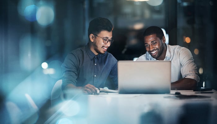 Deux hommes regardant un ordinateur portable sur une table