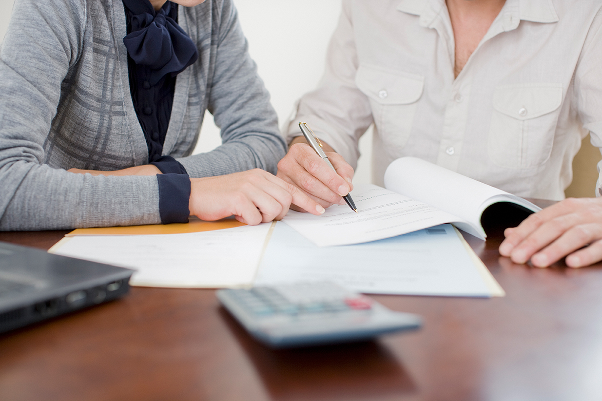 Two women work do paperwork in front of a calculator