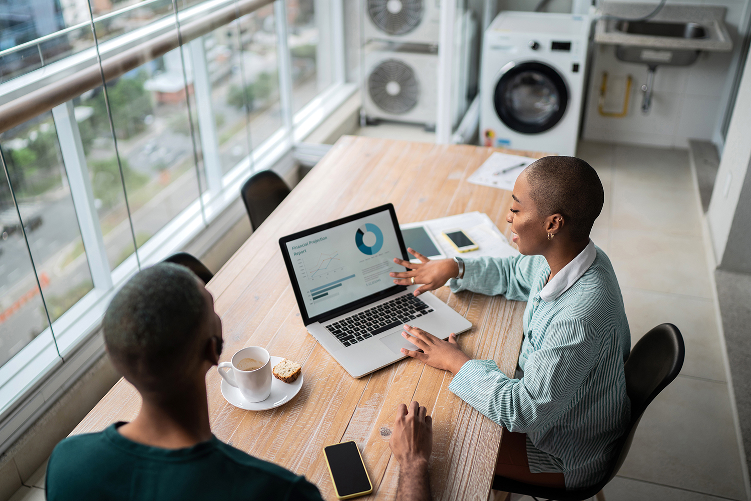 A man and a woman enjoy coffee in front of a laptop