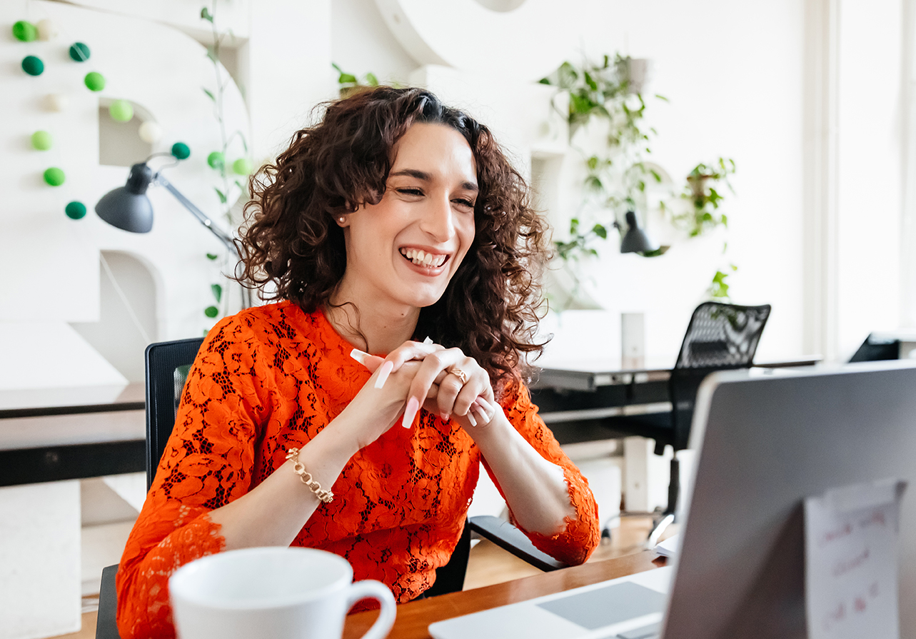 Femme aux cheveux bruns et à la chemise orange souriant après être devenue Membre