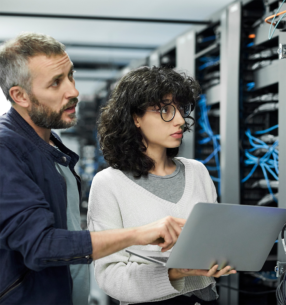 Two Cubeler members in an IT room checking IT installation security with a laptop
