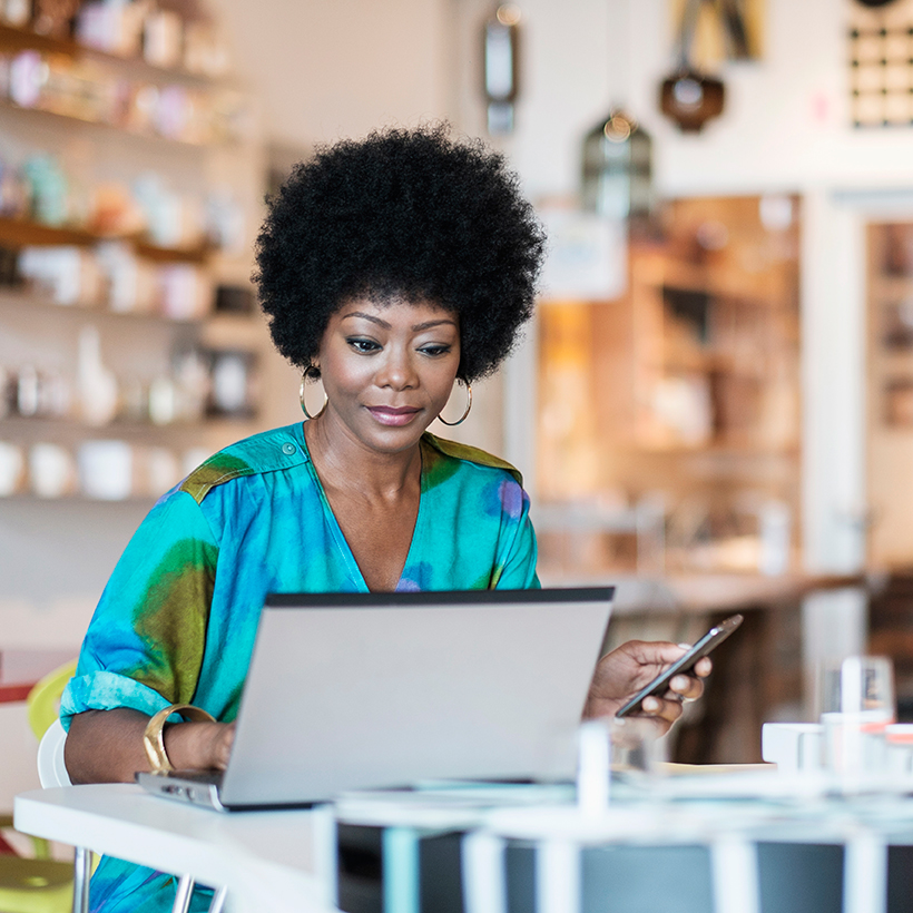 Une femme en chemise bleue cherchant des prêts pour commerce de détail sur un ordinateur portable.