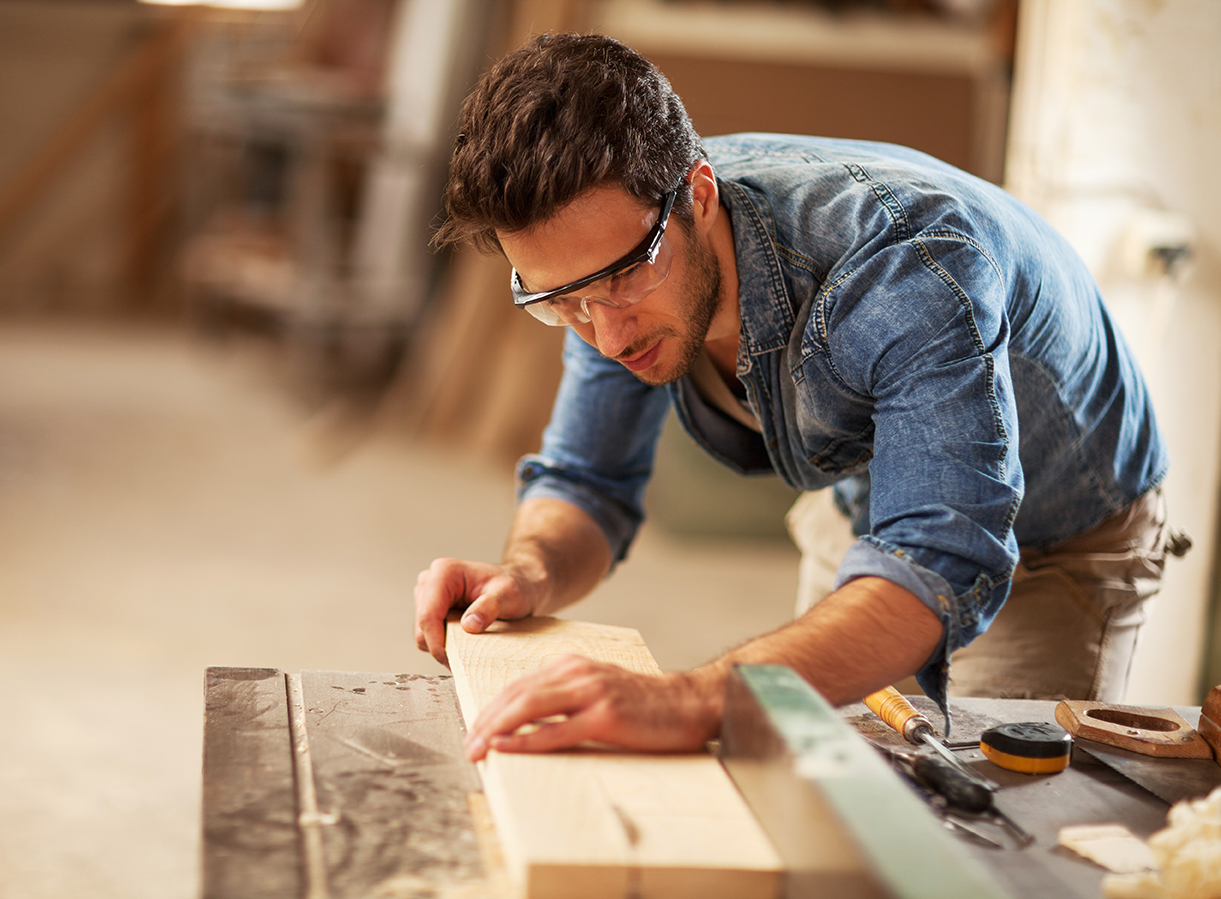 Un charpentier portant une chemise bleue et des lunettes de sécurité. 
